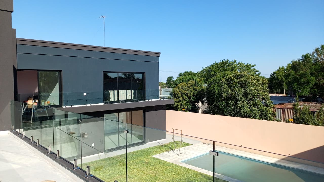 Casa moderna con ventanales y barandas de vidrio